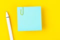 A blank blue notes paper and pen with a paper clip   on yellow background, for your text or message Royalty Free Stock Photo