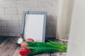 blank blue photo frame with vintage round clock and tulips on brick wall background Royalty Free Stock Photo