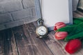 blank blue photo frame with vintage round clock and tulips on brick wall background Royalty Free Stock Photo