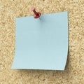 Blank blue sticky note pinned on a cork board