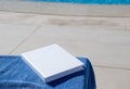 blank book for mockup design on lounger by the swimming pool