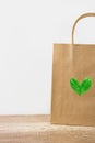 Blank brown craft paper bag on white wall background. Heart logo from leaves. Nature friendly style. Environmental conservation