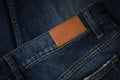 Blank brown leather label sewed on a blue denim jeans. Mock up jeans tag Royalty Free Stock Photo