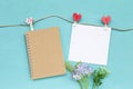 Blank brown notebook and white paper card with red heart design clip with flower on blue background