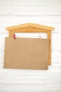 Blank brown paper hanging with house wooden decorate on white wa Royalty Free Stock Photo