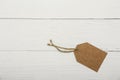 Blank brown price tag on on white wooden background. View from above. Blank brown cardboard price tag or label  on white b Royalty Free Stock Photo