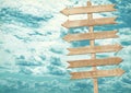 Blank brown wooden signpost against blue sky.