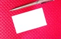 Blank business card and golden pen on burgundy background. A rectangle of white paper and a ballpoint pen lie on a burgundy Royalty Free Stock Photo