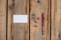 Blank business card, pen, and push pins against a wooden background. A white paper rectangle, three push pins, and a ballpoint pen Royalty Free Stock Photo