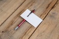 A blank business card and a red pen against a wooden background. A white paper rectangle and a ballpoint pen lie on top of old Royalty Free Stock Photo