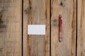 A blank business card and a red pen against a wooden background. A white paper rectangle and a ballpoint pen lie on top of old Royalty Free Stock Photo