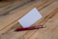 A blank business card and a red pen against a wooden background. A white paper rectangle and a ballpoint pen lie on top of old Royalty Free Stock Photo