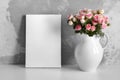 Blank canvas mockup on white table with flowers in pitcher on concrete wall background
