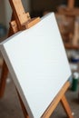 Blank canvas on wooden easel in art studio with blurred background Royalty Free Stock Photo