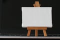 Blank canvas and wooden easel on laptop computer Royalty Free Stock Photo