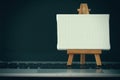 Blank canvas and wooden easel on laptop computer Royalty Free Stock Photo