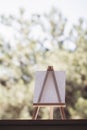 Blank canvas on wooden mini easel stands on windowsill in front of nature, art and inspiration concept