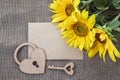 Blank card, bouquet of sunflowers, heart-lock and a key on a background of burlap.