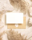 Card and enveelope near beige travertine stones and dried pampas grass top view, mockup Royalty Free Stock Photo