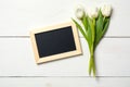 Blank card for invitation or congratulation with bunch of white tulips flowers on white wooden table. Vintage banner mockup for sp Royalty Free Stock Photo