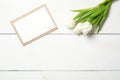 Blank card for invitation or congratulation with bunch of white tulips flowers on white wooden table. Vintage banner mockup for sp Royalty Free Stock Photo