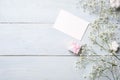 Blank card for invitation or congratulation, little gift box, bunch of gypsophila flowers on light blue wooden table. Banner mocku