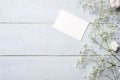 Blank card for invitation or congratulation, little gift box, bunch of gypsophila flowers on light blue wooden table. Banner mocku Royalty Free Stock Photo