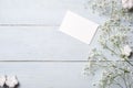 Blank card for invitation or congratulation, little gift box, bunch of gypsophila flowers on light blue wooden table. Banner mocku