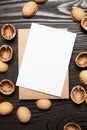 Blank card mockup with walnut shells and envelop on wooden background, top view, flat lay. White holiday card on brown table Royalty Free Stock Photo