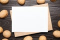 Blank card mockup with walnut shells and envelop on wooden background, top view, flat lay. White holiday card on brown table Royalty Free Stock Photo