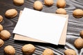 Blank card mockup with walnut shells and envelop on wooden background. White holiday card on brown table Royalty Free Stock Photo