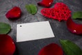 A blank card for a signature among the leaves of a rose and a red heart on a dark background. Valentine`s day or wedding.