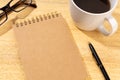 Blank Cardboard notepad on wooden desk with cup of coffee and eyeglasses