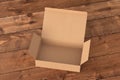 Blank cardboard wide flat box with opened hinged flap lid on dark wooden background.