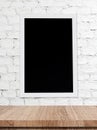 Blank chalk board over wooden table and white brick wall background Royalty Free Stock Photo