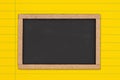 Blank chalkboard on bright yellow ruled line notebook paper background