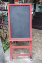 Blank chalkboard sign menu board with red frame and red stand in front of restaurant Royalty Free Stock Photo