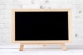 Blank chalkboard standing on white table over white brick wall b Royalty Free Stock Photo