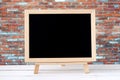 Blank chalkboard standing on white table over brick wall background Royalty Free Stock Photo