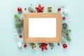 Blank Christmas photo frame with fir tree branches, holiday decorations on blue background. Mock up. Flat lay Royalty Free Stock Photo