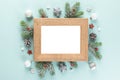 Blank Christmas photo frame with fir tree branches, holiday decorations, red berries on blue background. Mock up Royalty Free Stock Photo