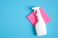 Blank cleaning spray bottle and pink rag on blue background. Flat lay, top view. House cleaning service and housekeeping concept Royalty Free Stock Photo