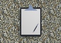 Blank clipboard with ballpen on gravel