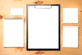 Blank clipboard, business card and notepads on wooden background.