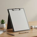 A blank clipboard is displayed on a wooden desk, angled upright. It holds a clean, Royalty Free Stock Photo