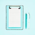 Blank clipboard mockup and ballpoint pens on light blue color background. Top view, copy space. Back to school, deadline, morning Royalty Free Stock Photo