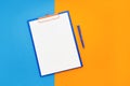 Blank clipboard mockup and blue pen on blue-orange color background. Top view, copy space. Back to school, deadline, morning Royalty Free Stock Photo