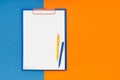 Blank clipboard mockup and two pens on blue-orange color background. Top view, copy space. Back to school, deadline, morning Royalty Free Stock Photo