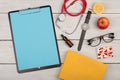 blank clipboard, pills, fruits, book, stethoscope, eyeglasses and watch on wooden background Royalty Free Stock Photo