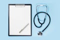 Blank clipboard with stethoscope on blue background Royalty Free Stock Photo